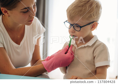 Special tests for tongue by using device. Speech therapist is with young boy indoors 137804428