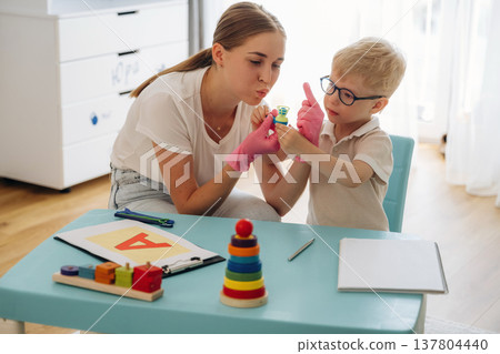 Speech therapist is with young boy indoors Speech therapist is with young boy indoors 137804440