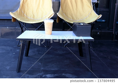 Ice coffee on table and camping chairs. Ice coffee on table and camping chairs. 137804495
