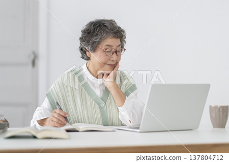 A senior woman staring at her laptop screen. 137804712