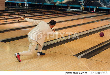 Throwing the ball. Man is playing bowling indoors Throwing the ball. Man is playing bowling indoors 137804915