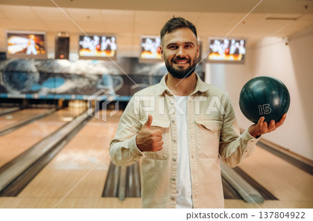Showing the ball, standing. Man is playing bowling indoors Showing the ball, standing. Man is playing bowling indoors 137804922