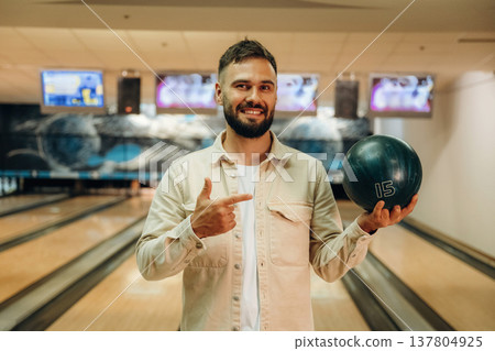 Holding the ball, standing. Man is playing bowling indoors Holding the ball, standing. Man is playing bowling indoors 137804925