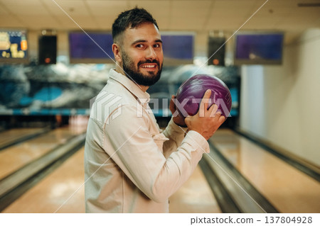 Holding the ball, standing. Man is playing bowling indoors 137804928