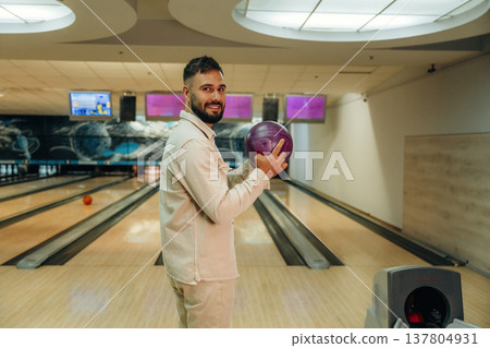 Holding the ball, standing. Man is playing bowling indoors Holding the ball, standing. Man is playing bowling indoors 137804931