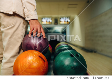 Taking the ball. Close up view of man that is playing bowling Taking the ball. Close up view of man that is playing bowling 137804944