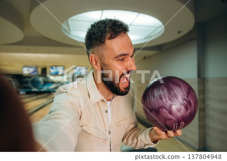Making a selfie, holding ball. Man is playing bowling indoors Making a selfie, holding ball. Man is playing bowling indoors 137804948