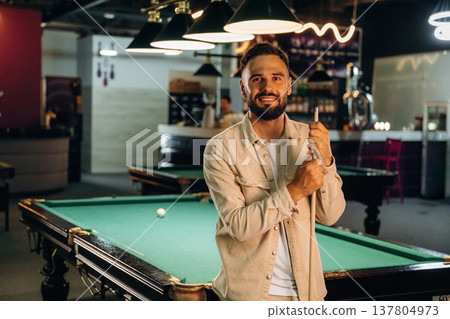Standing and posing. Handsome man with a pool table game Standing and posing. Handsome man with a pool table game 137804973