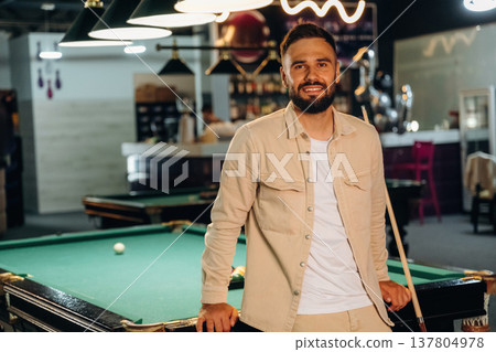 Standing and posing. Handsome man with a pool table game 137804978