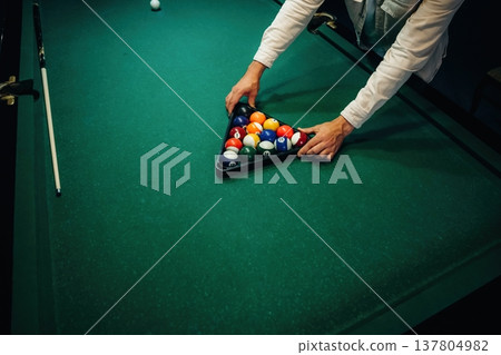 A man is placing billiard balls on a table A man is placing billiard balls on a table 137804982
