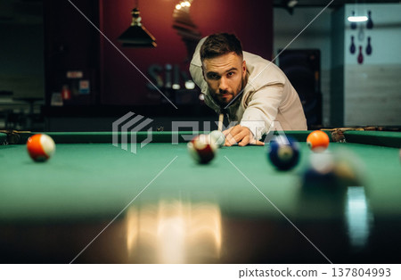 Using cue stick. Handsome man with a pool table game Using cue stick. Handsome man with a pool table game 137804993