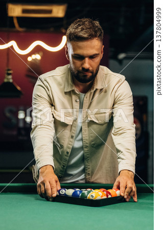 Getting ready, placing the balls. Handsome man with a pool table game Getting ready, placing the balls. Handsome man with a pool table game 137804999