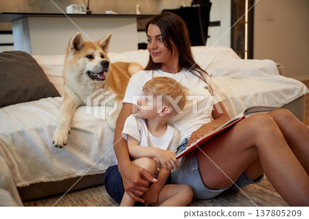 Looking at the pet. Mother with son and Shibu Inu dog are at home 137805209