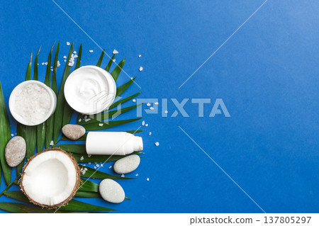 Coconut with jars of coconut oil and cosmetic cream on colored background. Top view. Free space for your text. Natural spa coconut cosmetics and organic treatment concept Coconut Spa composition 137805297