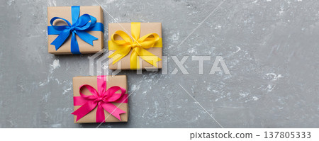 Holiday gift box wrapped in craft paper with colored bow on table background. Top view, flat lay, copy space 137805333