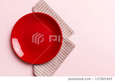 Top view on colored background empty round red plate on tablecloth for food. Empty dish on napkin with space for your design 137805405