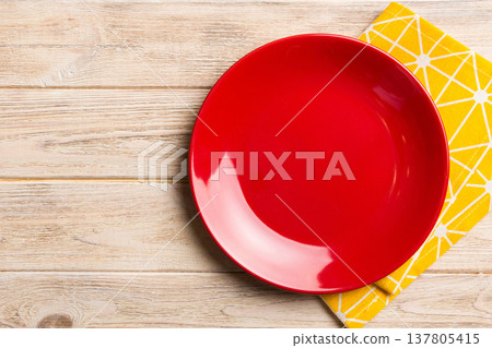 Top view on colored background empty round red plate on tablecloth for food. Empty dish on napkin with space for your design 137805415
