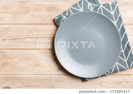 Top view on colored background empty round gray plate on tablecloth for food. Empty dish on napkin with space for your design 137805417