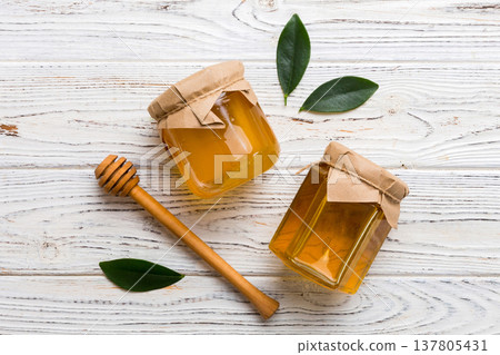 Honey jar with wooden honey dipper on white background top view with copy space. Delicious honey bottle Honey jar with wooden honey dipper on white background top view with copy space. Delicious honey bottle 137805431