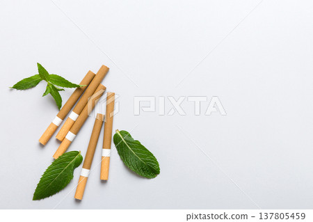 Menthol cigarettes and fresh mint leaves on colored background, Many cigarettes stacked together top view flat lay Menthol cigarettes and fresh mint leaves on colored background, Many cigarettes stacked together top view flat lay 137805459