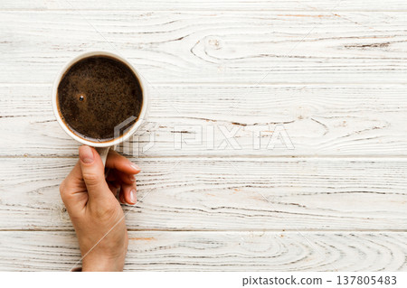 Minimalistic style woman hand holding a cup of coffee on Colored background. Flat lay, top view cappuccino cup. Empty place for text, copy space. Coffee addiction. Top view, flat lay 137805483