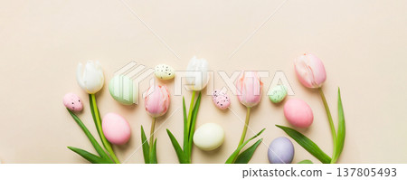 Happy Easter composition. Easter eggs on colored table with yellow Tulips. Natural dyed colorful eggs background top view with copy space 137805493