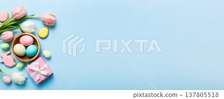 Easter frame with eggs, gift box and tulip on a colored background. The minimal concept. Top view Happy Easter composition. Card with a copy space of the place for the text 137805518