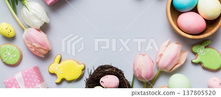 Easter frame with eggs, gift box and tulip on a colored background. The minimal concept. Top view Happy Easter composition. Card with a copy space of the place for the text 137805520