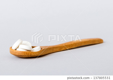 Heap of white pills on colored background. Tablets scattered on a table. Pile of red soft gelatin capsule. Vitamins and dietary supplements concept 137805531