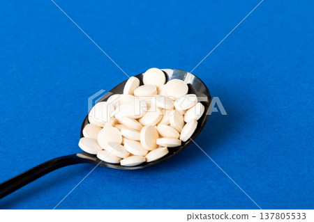 Heap of white pills on colored background. Tablets scattered on a table. Pile of red soft gelatin capsule. Vitamins and dietary supplements concept Heap of white pills on colored background. Tablets scattered on a table. Pile of red soft gelatin capsule. Vitamins and dietary supplements concept 137805533