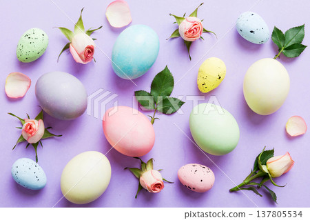 Happy Easter. Easter eggs on colored table with yellow roses. Natural dyed colorful eggs background top view with copy space Happy Easter. Easter eggs on colored table with yellow roses. Natural dyed colorful eggs background top view with copy space 137805534