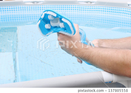 Man assembles a swimming pool vacuum cleaner and service and maintenance of the pool Man assembles a swimming pool vacuum cleaner and service and maintenance of the pool 137805558