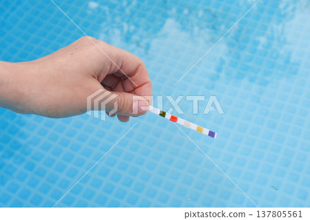 Analysis of the PH and chlorine of the water in a swimming pool in Summer. Check quality of water with test strip, comparing results Analysis of the PH and chlorine of the water in a swimming pool in Summer. Check quality of water with test strip, comparing results 137805561