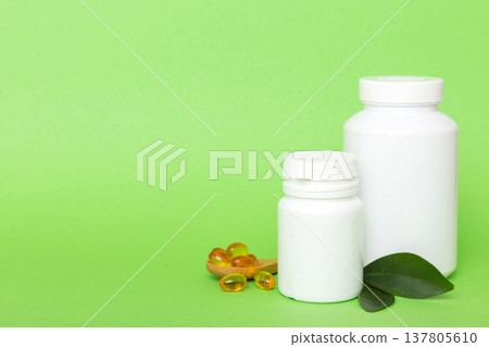 Omega-3 capsules lie in white bottle on a table with green leaves background. Fish oil tablets. Biologically active additives. omega 6, omega 9, vitamin A, E, D, vitamin D3 top view with copy space 137805610