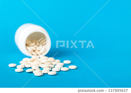 Medicine bottle and white pills spilled on a light background. Medicines and prescription pills flat lay background. White medical pills and tablets spilling out of a drug bottle Medicine bottle and white pills spilled on a light background. Medicines and prescription pills flat lay background. White medical pills and tablets spilling out of a drug bottle 137805637