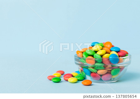 Multicolored candies in a bowl on a colored background. birthday and holiday concept. Top view with copy space Multicolored candies in a bowl on a colored background. birthday and holiday concept. Top view with copy space 137805654