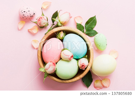 Happy Easter. Easter eggs in basket on colored table with yellow roses. Natural dyed colorful eggs background top view with copy space 137805680