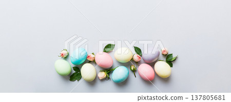 Happy Easter. Easter eggs on colored table with yellow roses. Natural dyed colorful eggs background top view with copy space Happy Easter. Easter eggs on colored table with yellow roses. Natural dyed colorful eggs background top view with copy space 137805681