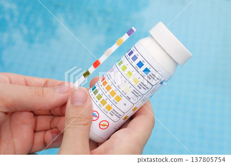 Analysis of the PH and chlorine of the water in a swimming pool in Summer. Check quality of water with test strip, comparing results Analysis of the PH and chlorine of the water in a swimming pool in Summer. Check quality of water with test strip, comparing results 137805754
