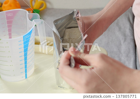 baby food and nutrition concept - mother hands with jar, spoon and bowl preparing cereal from powder close up baby food and nutrition concept - mother hands with jar, spoon and bowl preparing cereal from powder close up 137805771