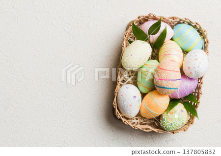 Colorful Easter eggs in wicker basket against colored background, closeup. top view with copy space Colorful Easter eggs in wicker basket against colored background, closeup. top view with copy space 137805832