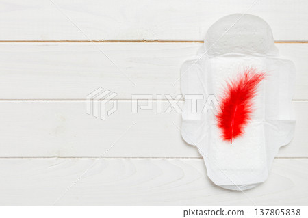 Women hygiene products or Sanitary pad with red feather on colored background. Pastel color. Closeup. Empty place for text. Female daily hygiene Women hygiene products or Sanitary pad with red feather on colored background. Pastel color. Closeup. Empty place for text. Female daily hygiene 137805838
