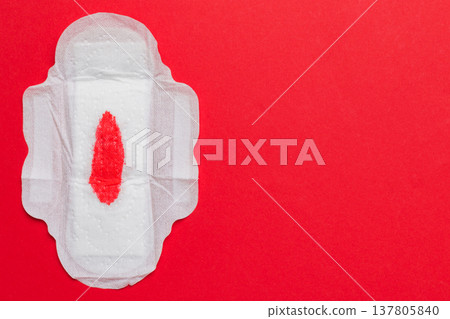 Women hygiene products or Sanitary pad with red feather on colored background. Pastel color. Closeup. Empty place for text. Female daily hygiene Women hygiene products or Sanitary pad with red feather on colored background. Pastel color. Closeup. Empty place for text. Female daily hygiene 137805840