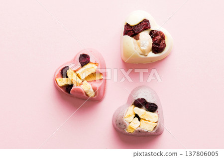 chocolate sweets in the form of a heart with fruits and nuts on a colored background. top view with space for text, holiday concept chocolate sweets in the form of a heart with fruits and nuts on a colored background. top view with space for text, holiday concept 137806005
