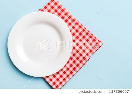 Top view on colored background empty round white plate on tablecloth for food. Empty dish on napkin with space for your design 137806007