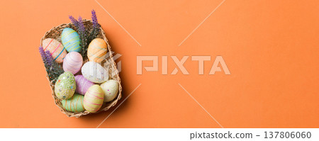 Colorful Easter eggs in wicker basket against colored background, closeup. top view with copy space Colorful Easter eggs in wicker basket against colored background, closeup. top view with copy space 137806060