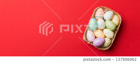 Colorful Easter eggs in wicker basket against colored background, closeup. top view with copy space Colorful Easter eggs in wicker basket against colored background, closeup. top view with copy space 137806062