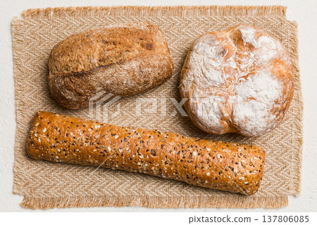 Assortment of freshly baked bread with napkin on rustic table top view. Healthy unleavened bread. French bread Assortment of freshly baked bread with napkin on rustic table top view. Healthy unleavened bread. French bread 137806085