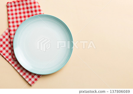 Top view on colored background empty round blue plate on tablecloth for food. Empty dish on napkin with space for your design Top view on colored background empty round blue plate on tablecloth for food. Empty dish on napkin with space for your design 137806089
