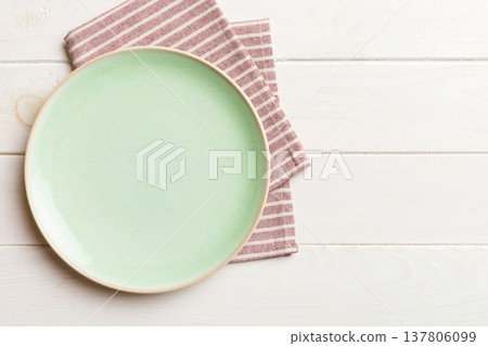 Top view on colored background empty round green plate on tablecloth for food. Empty dish on napkin with space for your design Top view on colored background empty round green plate on tablecloth for food. Empty dish on napkin with space for your design 137806099